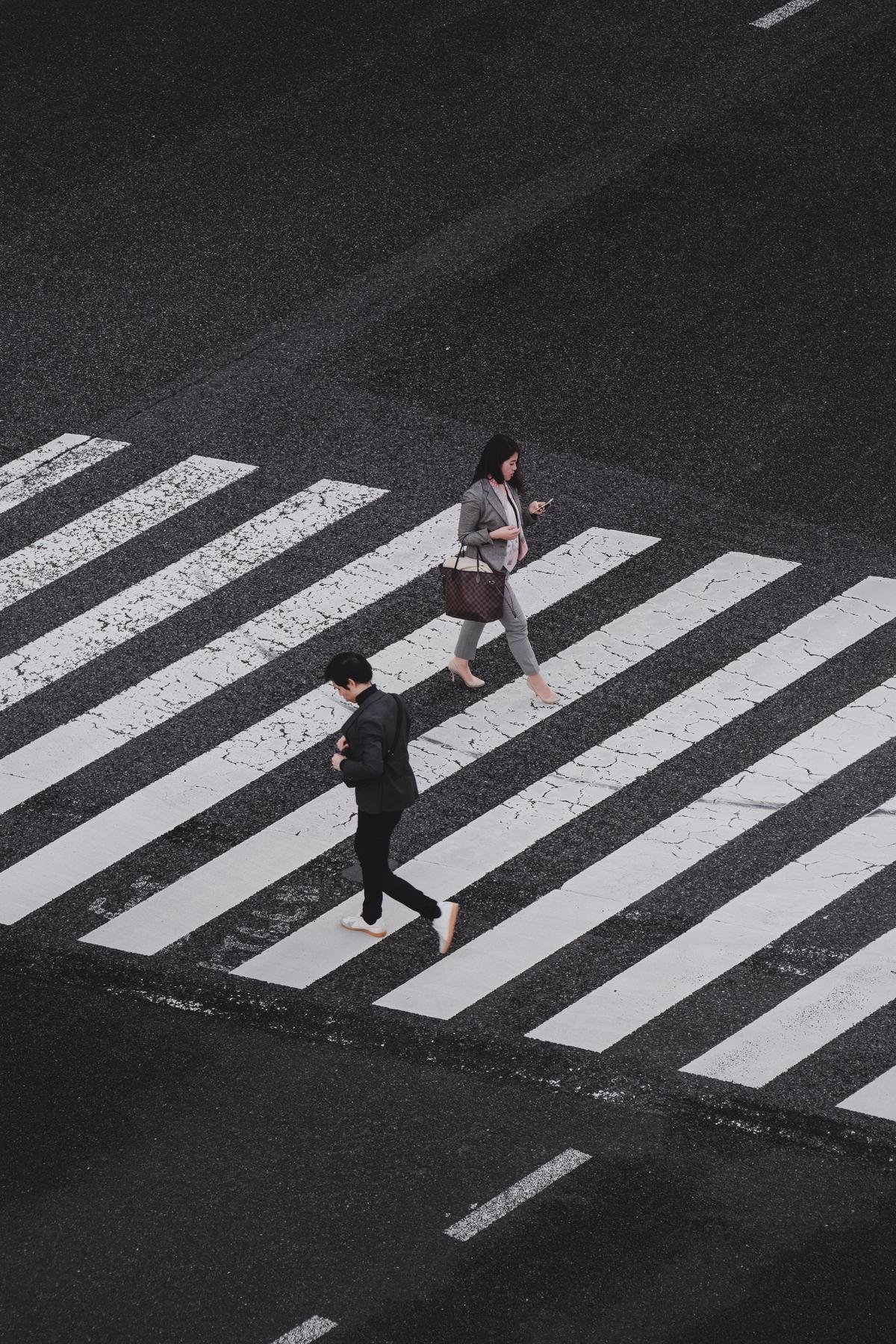 Image of a child with autism being led by a parent across a zebra-crossing with bright background.
