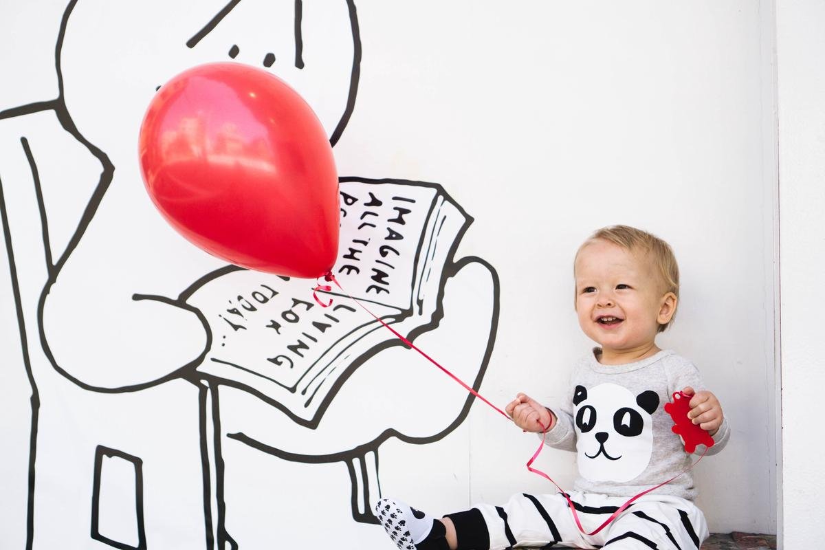 A smiling child holding a book and pointing to pictures, depicting the joy of expressive language development.