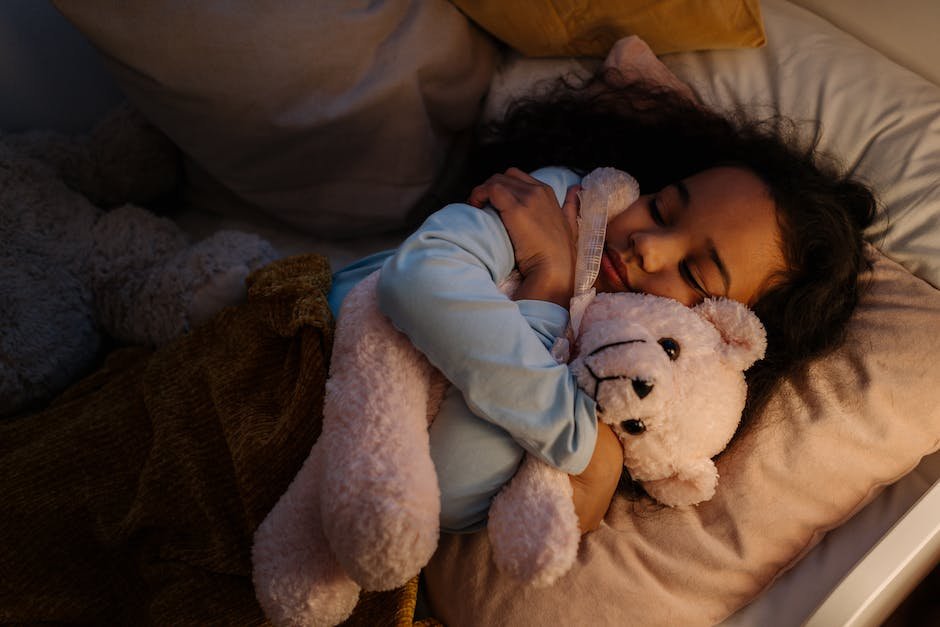 A peaceful image depicting a child sleeping peacefully, surrounded by soft pillows and a cozy blanket with a teddy bear by their side.